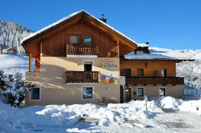 a building with a balcony in the snow at B&B Apartments La Palsa in San Cassiano