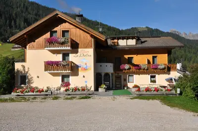 a house with flowers on the balconies in front of it at B&B Apartments La Palsa in San Cassiano