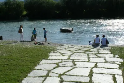 a group of people sitting on the bank of a river at Gruppenhaus Thalackerhof in Brunico