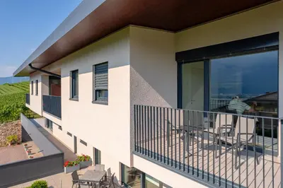 a balcony of a building with tables and chairs at Tholr - Ferienwohnungen - Tramin in Termeno