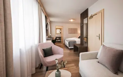a hotel room with a bed and a couch and a chair at Appartementhaus Residence Hirzer in Tirolo