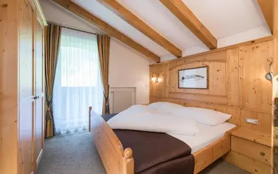 a bedroom with a bed with a wooden wall at Appartementhaus Residence Hirzer in Tirolo