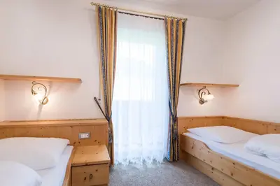 a bedroom with two beds and a window at Appartementhaus Residence Hirzer in Tirolo