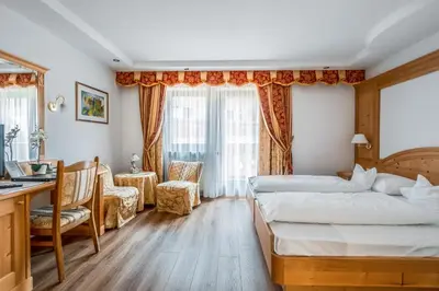 a hotel room with two beds and a desk at Garni Franca b&b in Selva di Val Gardena
