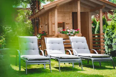 three chairs sitting in the grass in front of a house at Garni Franca b&b in Selva di Val Gardena