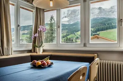 a table with a bowl of fruit on it in a room with windows at Medesc in La Villa