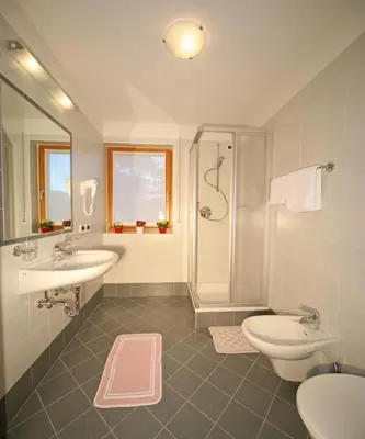 a bathroom with two sinks and a shower and a toilet at Medesc in La Villa