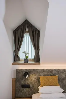 a bedroom with a window with a plant in a vase at Gasthof Albergo Dolomiten in Braies