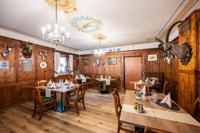 a restaurant with wooden walls and tables and chairs at Gasthof Albergo Dolomiten in Braies