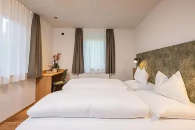 two beds in a hotel room with white sheets at Gasthof Albergo Dolomiten in Braies