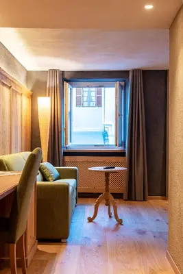 a living room with a couch and a table and a window at Hotel Goldenes Roessl-adults only in Bressanone