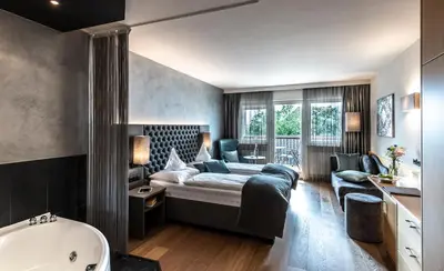 a bedroom with a bed and a tub in a room at Hotel Das Stachelburg in Parcines