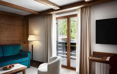 a living room with a blue couch and a window at Hotel Tyrol in Selva di Val Gardena