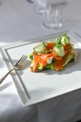 a sandwich on a white plate with a fork at Hotel Tyrol in Selva di Val Gardena