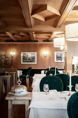 a restaurant with white tables and green chairs at Hotel Tyrol in Selva di Val Gardena