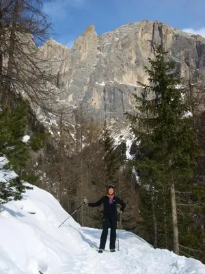 a woman on skis in the snow in front of a mountain at Hotel Albe in Rocca Pietore