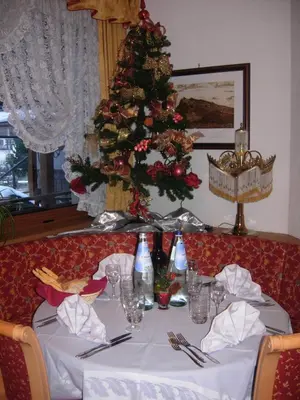 a dining table with a christmas tree in the background at Hotel Albe in Rocca Pietore