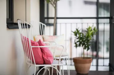 two white chairs with pillows sitting on a balcony at Mondschein Rooms in Lana