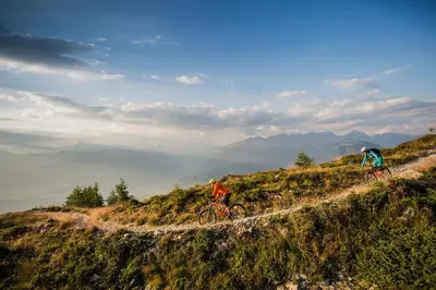 two people riding bikes on a grassy hill at Mondschein Rooms in Lana