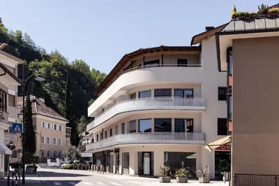 a white building with a balcony on a street at Mondschein Rooms in Lana
