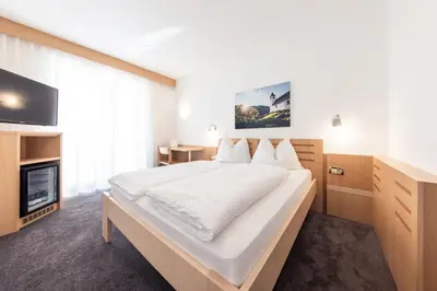 a bedroom with a large bed and a tv at Mondschein Rooms in Lana