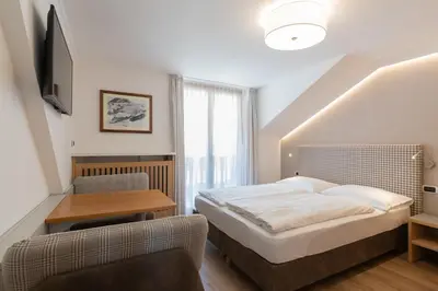 a bedroom with a bed and a table and a chair at Villa Aurelia in Ortisei