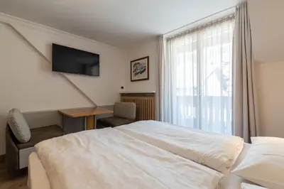 a bedroom with a bed and a desk and a television at Villa Aurelia in Ortisei