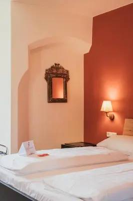 a bedroom with a bed with an orange wall at Hotel Traube in Bressanone