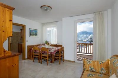 a dining room with a table and a balcony at Residence Villa Boschetto in Carano