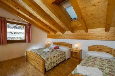 two beds in a room with wooden ceilings at Residence Villa Boschetto in Carano