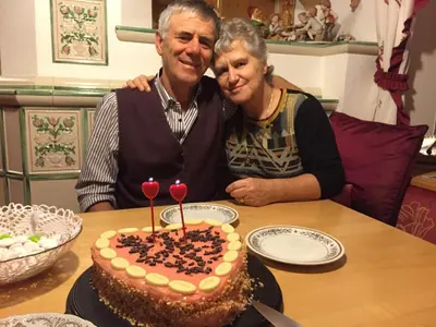 a man and a woman sitting at a table with a cake at Residence Villa Boschetto in Carano