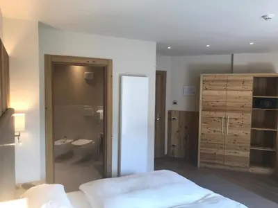 a bedroom with a bed and a bathroom with a toilet at Hotel Al Forte in Arabba