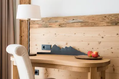 a desk with a lamp and two apples on a plate at Vitalhotel Dosses in Santa Cristina in Val Gardena