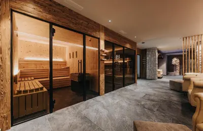 a room with a bar with glass doors at Vitalhotel Dosses in Santa Cristina in Val Gardena