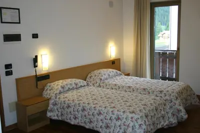 a bedroom with two beds and a table and chairs at Hotel Orsa Maggiore in Falcade