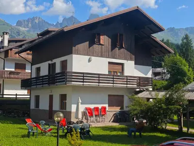 a house with red chairs in front of it at Hotel Orsa Maggiore in Falcade