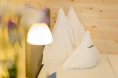 a row of pillows on a bed with a lamp at Hotel Kompatscherhof in Luson