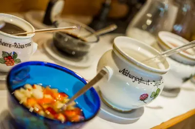 a table with two cups and a bowl of food at Hotel Kompatscherhof in Luson
