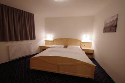 a bedroom with a wooden bed with two lights on the wall at Villa Hubertus in Ortisei