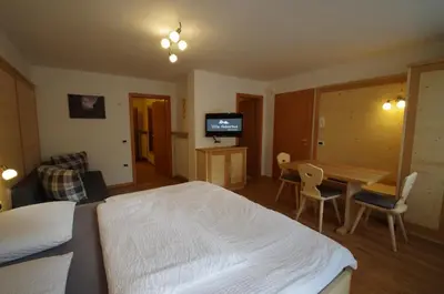 a bedroom with a bed and a table and a television at Villa Hubertus in Ortisei