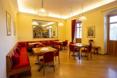 a restaurant with red seats and tables and a mirror at Hotel Salegg in Siusi