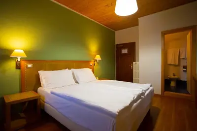 a bedroom with a large white bed with a green wall at Hotel Salegg in Siusi