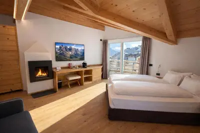 a hotel room with two beds and a desk and a desk at Hotel Villa Rosa in Campitello di Fassa