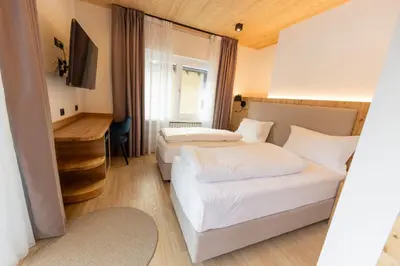 a hotel room with two beds and a desk at Hotel Villa Rosa in Campitello di Fassa