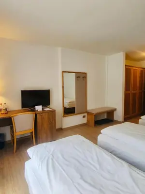 a hotel room with two beds and a desk and a television at Hotel Villa Rosa in Campitello di Fassa