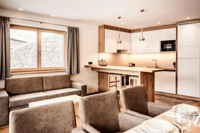 a bedroom with a bed and a desk and windows at Luxury Chalet Plazola in Selva di Val Gardena