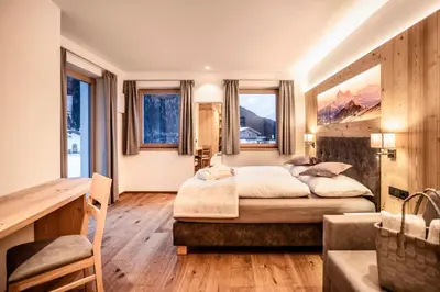 a kitchen with white cabinets and a large wooden island at Luxury Chalet Plazola in Selva di Val Gardena