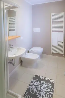 a white bathroom with a toilet and a sink at Appartamenti Regina in Alleghe