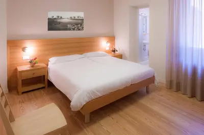 a bedroom with a large white bed and two tables at Appartamenti Regina in Alleghe