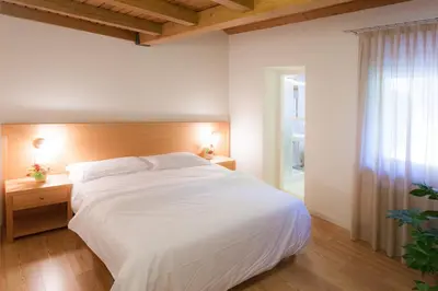 a bedroom with a large white bed and a window at Appartamenti Regina in Alleghe